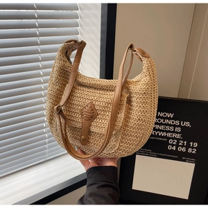 Detail of hand-woven straw shoulder bag with brown leather accents and half-moon shape
