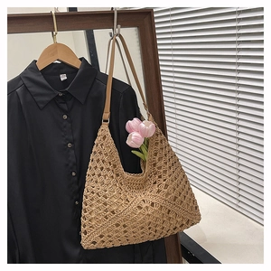 Close-up of khaki straw shoulder bag featuring geometric hollow crochet and leather straps