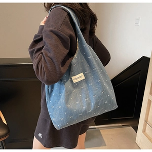 Detail of light blue denim tote bag with white heart and bow prints on model