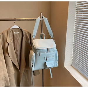 Close-up of light blue leather backpack with multiple metal zippers and large storage pockets