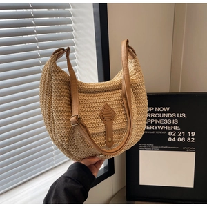 Detail of hand-woven beige straw hobo bag with adjustable brown leather shoulder strap