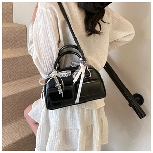Close-up of black bowling bag with lace bows and plaid ribbons on model in white dress