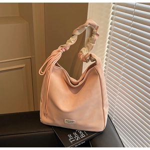 Detail of soft pink tote bag featuring tassel accents and cloud-shaped pleated handles