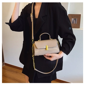 Detail of beige structured crossbody bag featuring a gold square buckle and chain strap