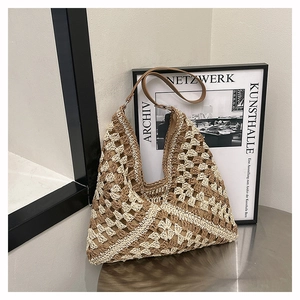 Detail of hollow geometric crochet pattern and brown leather strap on hobo straw bag