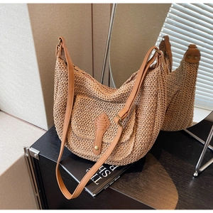 Detail view of the khaki woven straw dumpling bag featuring a flap pocket and leather strap