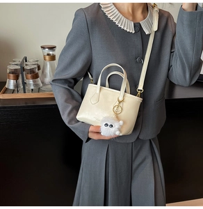 Détail du mini sac seau blanc crème avec charm monstre poilu et bandoulière longue