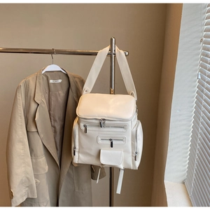 Close-up of cream white backpack with multiple metal zippers and large capacity design