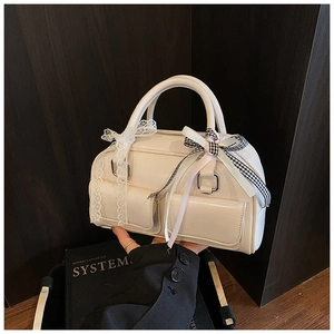Detail of cream Boston bag with lace bows and twin front pockets on dark wood