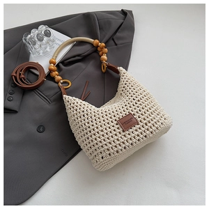 Detail of off-white woven shoulder bag with wooden bead handle and leather strap