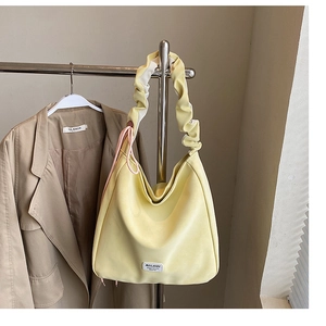 Detail of soft yellow tote bag with pleated handle and MULAIDI brand label on hanger