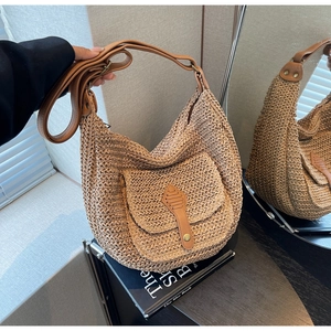 Close-up of woven straw handbag with brown leather strap and vintage metal buckle detail