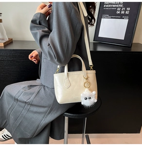 Détail du sac seau crème avec quincaillerie dorée et porte-clés en peluche blanche