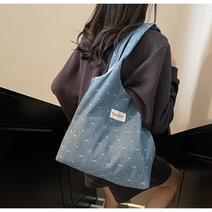 Detailed denim tote bag texture featuring white bow heart patterns and logo patch