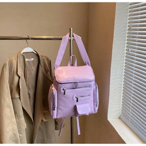Detail of purple multi-pocket quilted backpack with silver zippers on a coat hanger