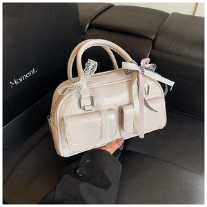 Detail of beige Boston bag showing lace trim and checkered bow with pink ribbon accents