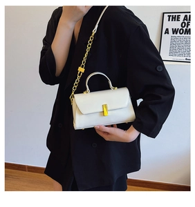 Close-up of a white leather crossbody bag with gold chain strap on a black suit