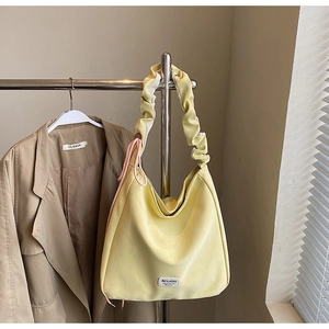 Close-up of a pale yellow Hobo tote bag with pleated shoulder strap and pink side cords