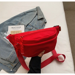 Detail of red canvas crossbody bag with dual zippers and adjustable wide strap