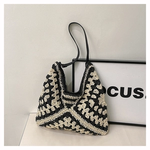 Detail view of woven crochet tote bag with black and white patterns and slim shoulder straps