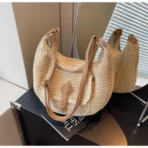 Detail of straw woven hobo bag featuring brown leather pocket and dual shoulder straps