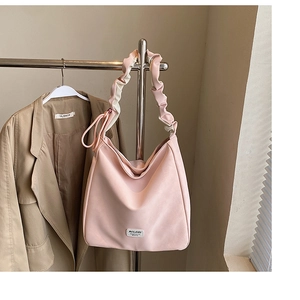 Detail view of pink tote bag with ruched shoulder strap on khaki blazer outfit