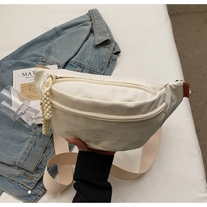 Detail of off-white canvas chest bag with embroidered logo and adjustable strap