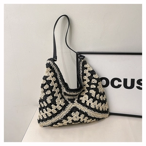 Close-up of contrast woven crochet pattern and black leather strap on a hobo bag