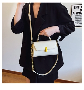 Detail of white minimalist square bag showing golden metal buckle and chain accents