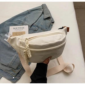 Detail of off-white canvas waist bag with woven rope zipper and orange label
