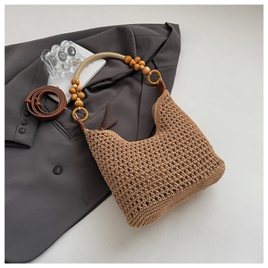 Detail of hand-woven crochet texture with wooden bead handle and leather shoulder strap