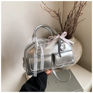 Detail of silver metallic Boston bag with pocket design and lace bow accessories