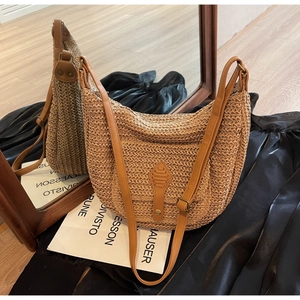 Detail of straw woven tote with brown leather strap and metal ring attachment