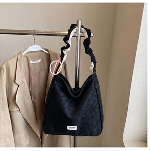 Detail of black matte hobo bag featuring a pleated black and white cloud shoulder strap