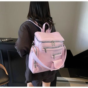 Detail of pink multi-pocket backpack showing functional zippers and wide shoulder strap
