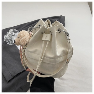 Detail of white drawstring bucket bag with shiny PU leather and cute puppy charm