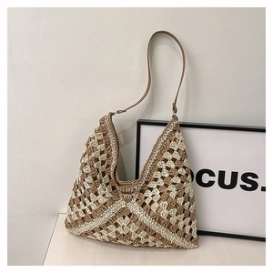 Close-up of handmade checkered straw shoulder bag with elegant brown leather strap