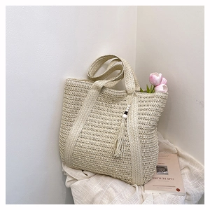 Detailed close-up of woven paper tote bag texture with boho fringe and wooden beads