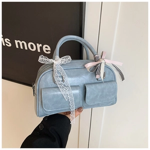 Detail of light blue Boston bag featuring front pockets and decorative lace bow