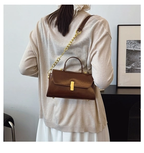 Model view of a vintage brown leather crossbody bag with gold chain and buckle detail