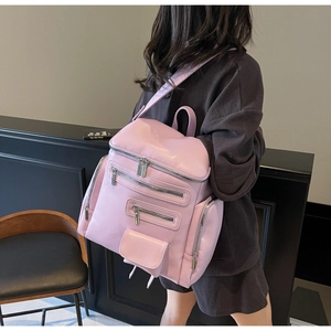 Detail view of pink synthetic leather backpack with silver zippers worn by a model