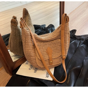 Detailed close-up of straw hobo bag showing woven texture and brown faux leather strap