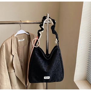 Detail of a large black matte tote bag with unique black and white scrunchie shoulder strap