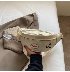 Dettaglio borsa a tracolla panna con ricamo a forma di orso e cinturino in tessuto spesso