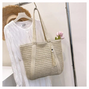Detail of hand-woven straw tote bag with beaded fringe tassel and mesh texture
