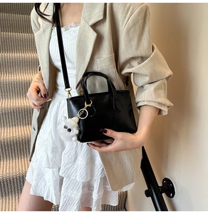 Sac seau en cuir noir avec pendentif peluche présenté par un mannequin en décor réel