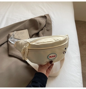 Elegante marsupio bianco crema con ricamo a fumetti su sfondo dai toni neutri caldi