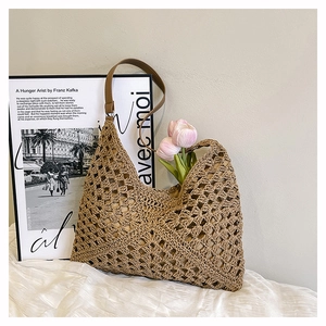 Detail of hand-woven hollow geometric pattern on straw tote bag with leather strap