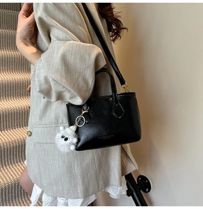 Détail d'un sac seau en cuir noir texturé avec un joli pendentif agneau en peluche blanche
