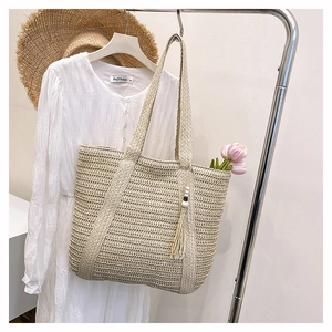 Close-up of straw woven tote bag with fringe charm and tulip accent for summer vibes